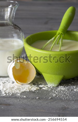 Pancake batter mix in a green bowl on the wood background.