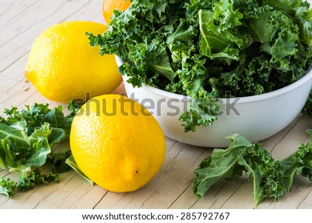 Closeup of bowl with fresh cut kale and orange and lemon - ingredients for cold breakfast pops.