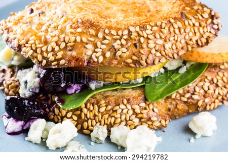 Closeup of blue cheese sandwich with slices of a pear, spinach and toasted bread.