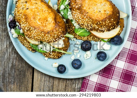 Closeup of blue cheese sandwich with slices of a pear, spinach and toasted bread.