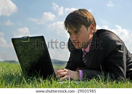 Businessman working with a laptop outdoor on grass