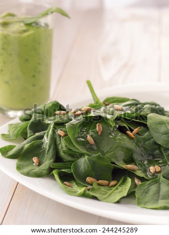 Spinach Salad with sunflower seeds and green smoothie in background.