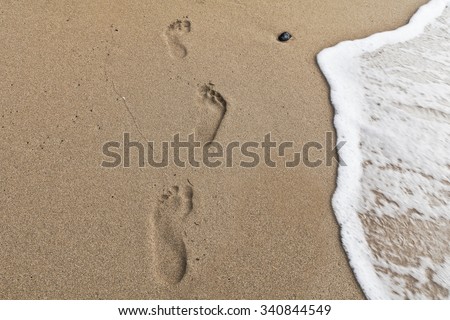 Detail of footprints on the sand and sea