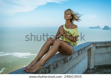 Girl sitting on the seacoast with windy hairs