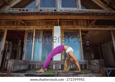 Woman make morning yoga stretching exercise near the wooden house, pose of bridge
