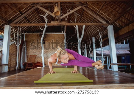 Woman make morning yoga exercise on the wooden terrace, ashtavakrasana pose