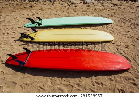 Red, yellow and green surf boards on yellow sand beach