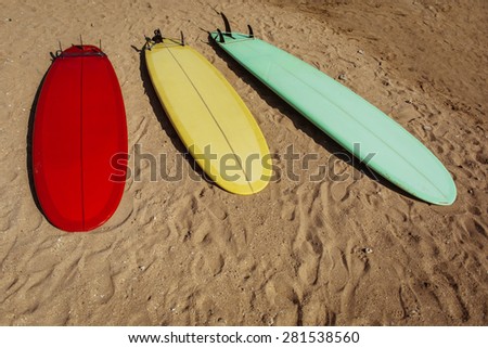 Red, yellow and green surf boards on yellow sand beach