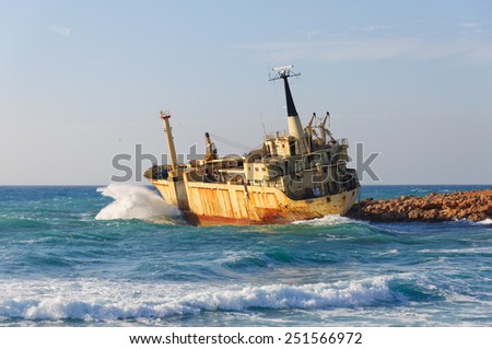 large rusty ship on the shore during a storm