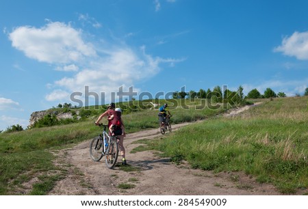 Family with young children on a mountain bike ride on dirt roadagainst a beautiful sky.