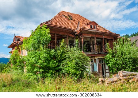 Old abandoned stone house with a leaky roof tiles in the Carpathians. Green vegetation and hills around