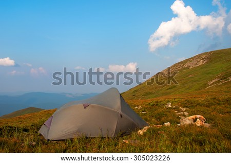 The gray tent in high mountains against the sky