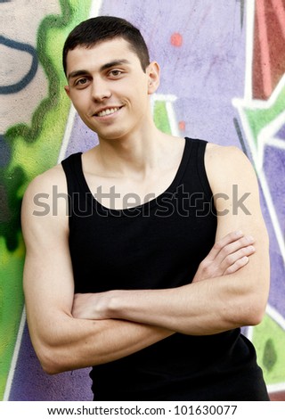 Teen boy near graffiti wall.