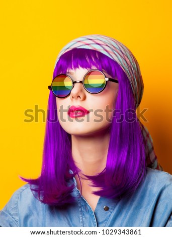 Young girl with purple hair and rainbow on suglasses on yellow background