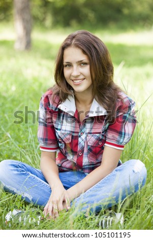 Beautiful teen girl in the park at green grass.