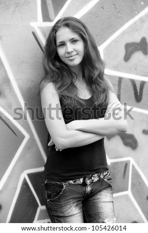 Style teen girl near graffiti background. Photo in black and white style.