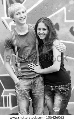 Style teen couple near graffiti background. Photo in black and white style.