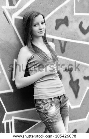 Style teen girl near graffiti background. Photo in black and white style.