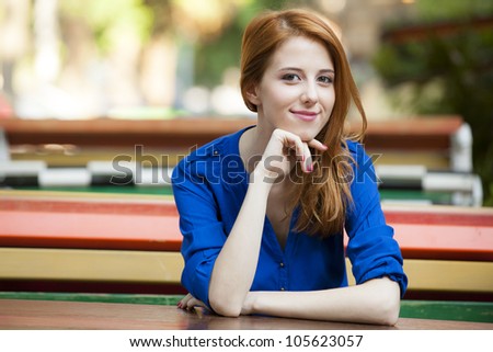 Style redhead girl sitting on the bench in the cafe