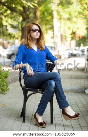 Style redhead girl sitting in the chair in the cafe
