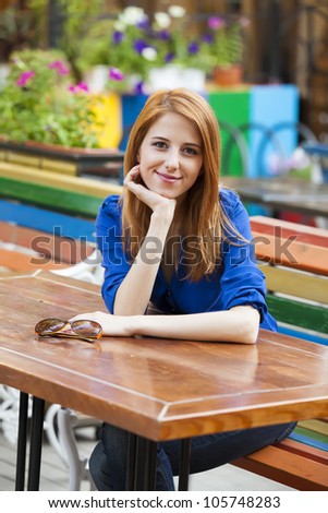 Style redhead girl sitting on the bench in the cafe