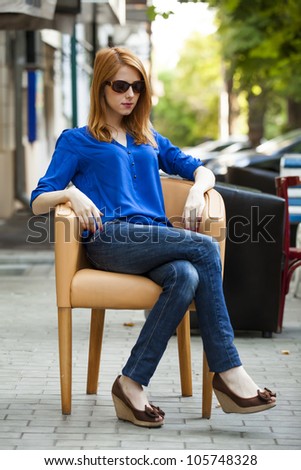 Style redhead girl sittin in the chair in the cafe