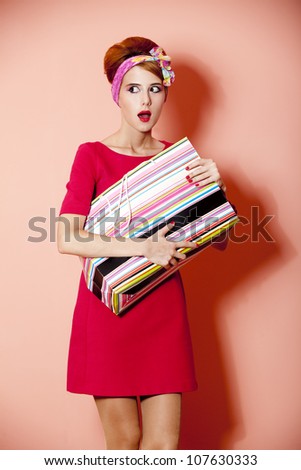 Style redhead girl with shopping box at pink background.