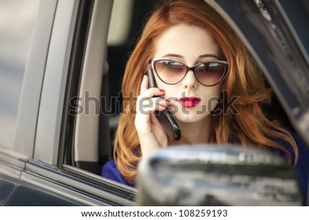 Beautiful redhead businesswoman calling by phone in the car.