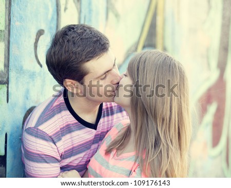 Young couple kissing near graffiti background.