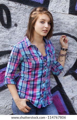 Style teen girl standing near graffiti wall.