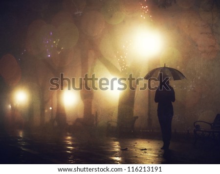 Single girl with umbrella at night alley. Photo with noise.