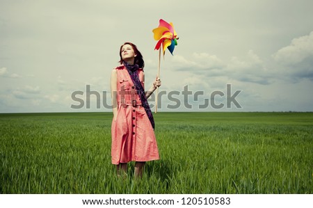 Young women with toy wind turbine at green wheat field.