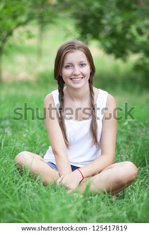 Beautiful teen girl in the park at green grass.