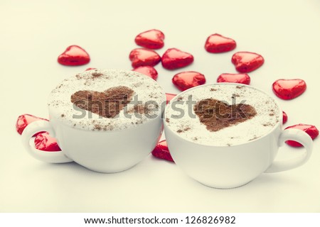 Two cup of coffee with heart symbol and candy around.