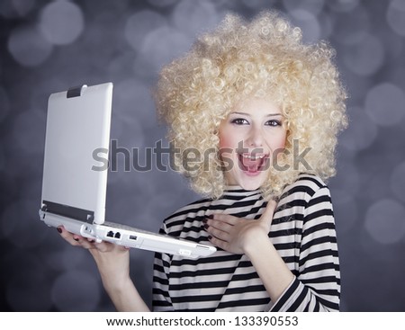 Portrait of funny girl in blonde wig with laptop. Studio shot.