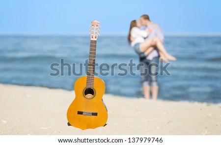 Portrait of young man and woman on a beach and guitar.