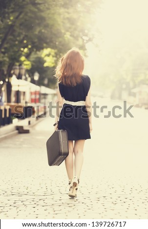 Young woman with suitcase walking on the city street