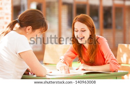 Two girls sitting in the cafe and looking in menu.