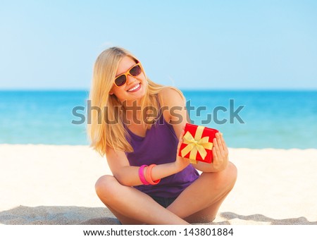 Blonde girl with gift at the beach.