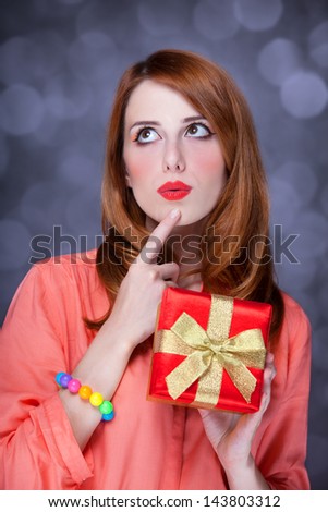 Redhead girl with present box. Bokeh.