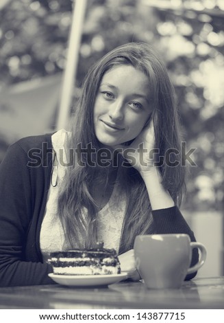 Style girl with cake and cup sitting in the cafe. Photo in black and white style.
