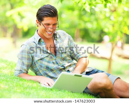 Student with laptop at green grass