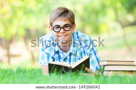 Teen boy with books in the park.
