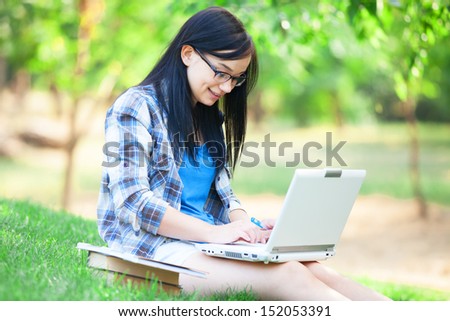 Teen girl with laptop in the park.