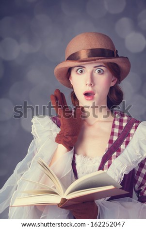 Beautiful redhead women with book. Photo in retro style with bokeh at background.