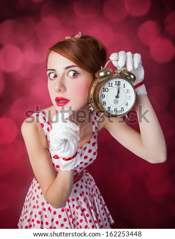 Beautiful redhead women with clock. Photo in retro style with bokeh at background.