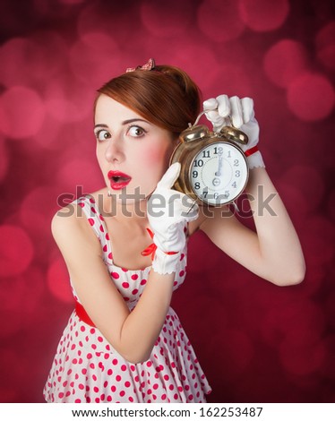 Beautiful redhead women with clock. Photo in retro style with bokeh at background.