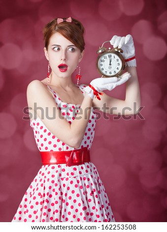 Beautiful redhead women with clock. Photo in retro style with bokeh at background.