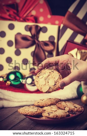 Female hand holding cookie at christmas gift background