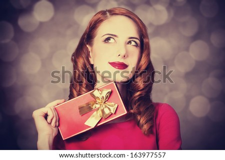 Redhead women with gift. Photo with bokeh at background.